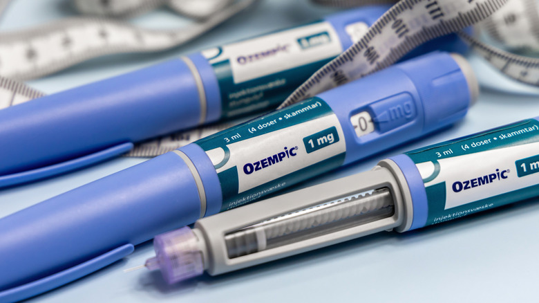 Three Ozempic pens with a tailor's tape measure