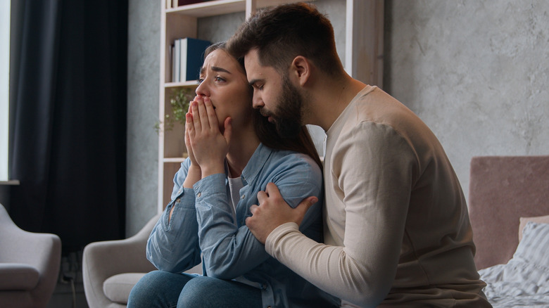 Woman crying while her male partner supports her