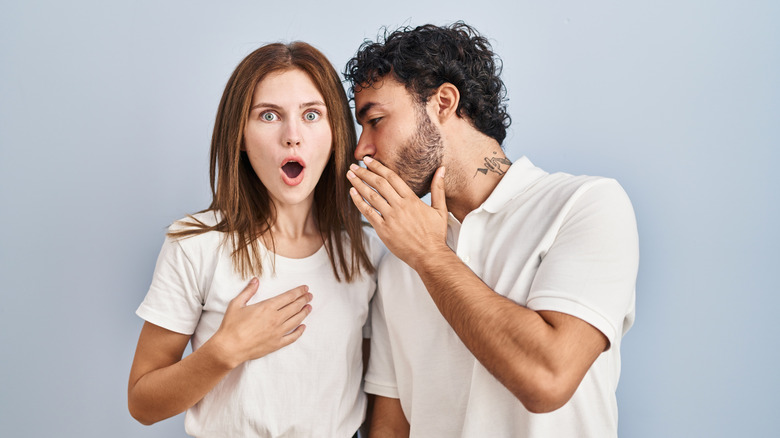 Young couple wearing casual clothes standing together hand on mouth telling secret rumor