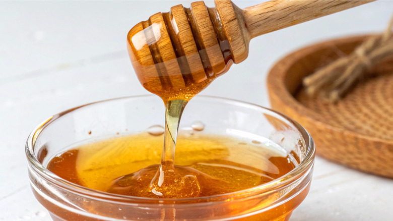 close-up of a honey dipper over a jar of honey