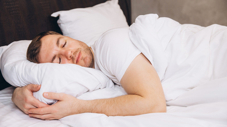 Man sleeping, cradling pillow
