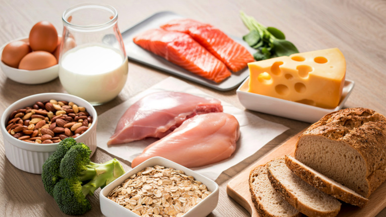 A collection of foods including chicken, bread, salmon, cheese, eggs, and nuts.