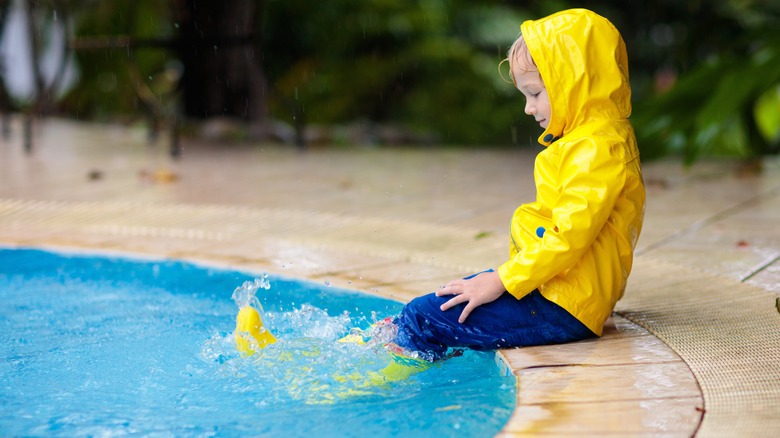 Child playing outdoors in tropical storm.