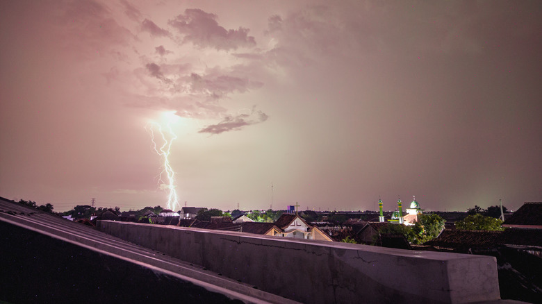 A bolt of lightning strikes the ground near a city
