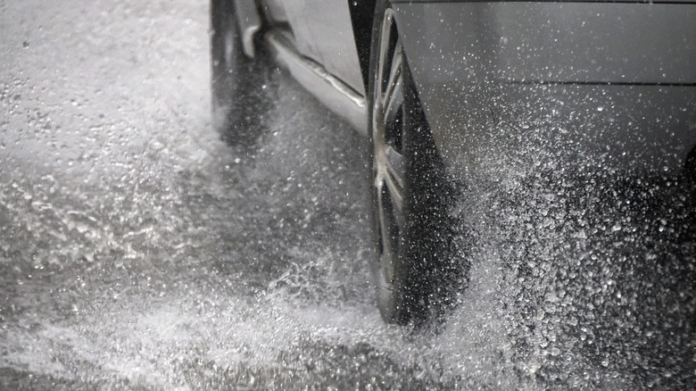 A Car tire aquaplaning under heavy rain detail