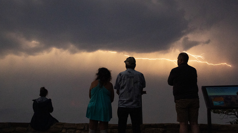 Visitors watch from the South Rim of the Grand Canyon near the Yavapai Geology Museum as a thunderstorm passes