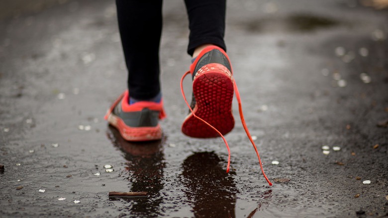 Person wearing shoes in rain with one lace untied