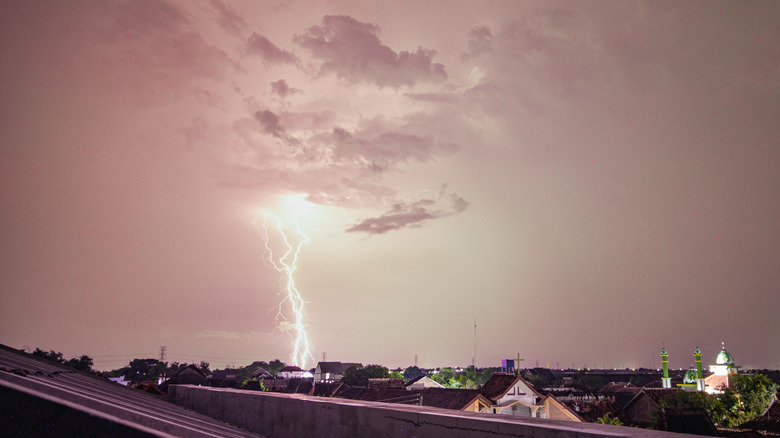 A bolt of lightning strikes the ground near a city