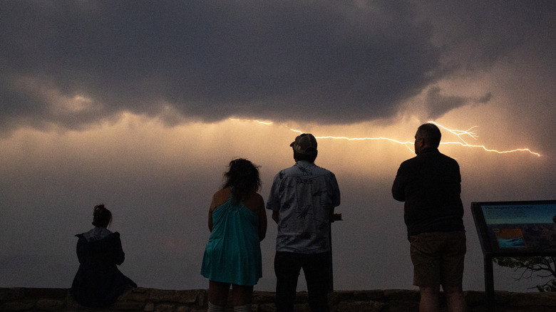 Visitors watch from the South Rim of the Grand Canyon near the Yavapai Geology Museum as a thunderstorm passes