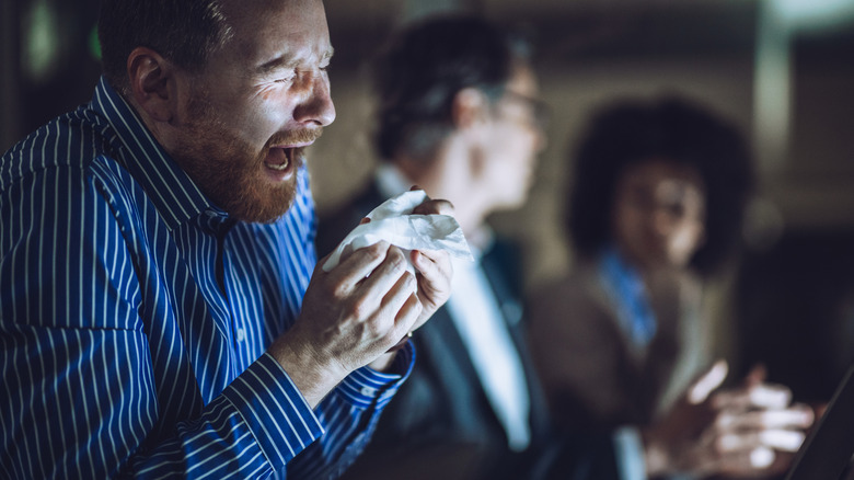 Man sneezing during a business meeting