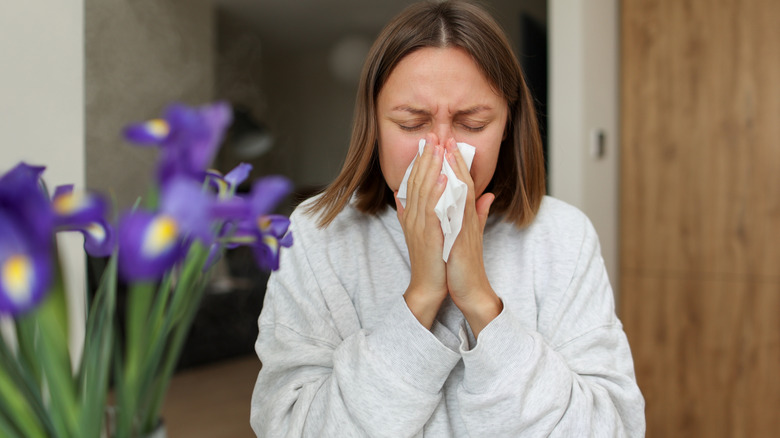 Woman sneezing into a tissue.