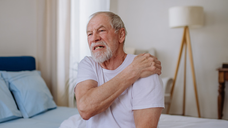 A bearded man is having pain on his shoulder
