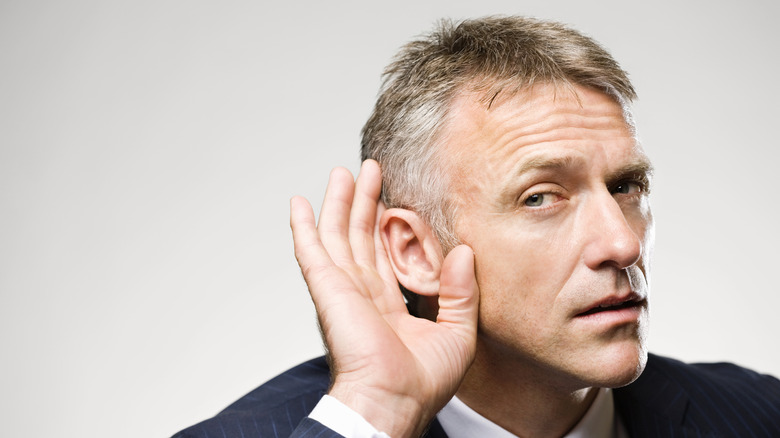 A man is holding his hand to his ear while listening