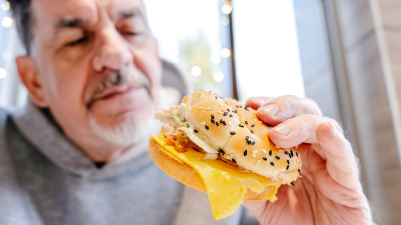 A man is looking suspiciously at a burger