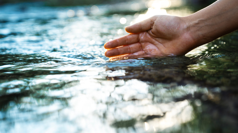 A hand is touching flowing water