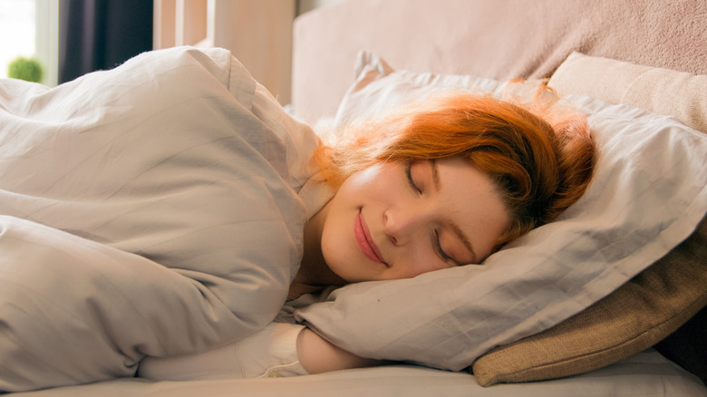 A woman is sleeping happily in the bed
