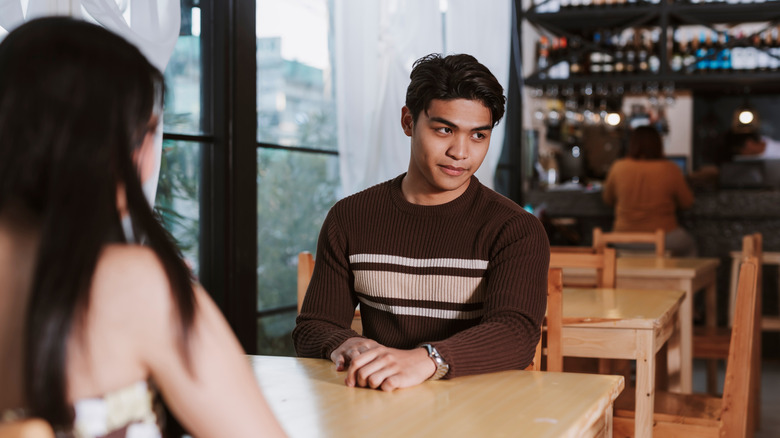 A man is avoiding eye contact with his date