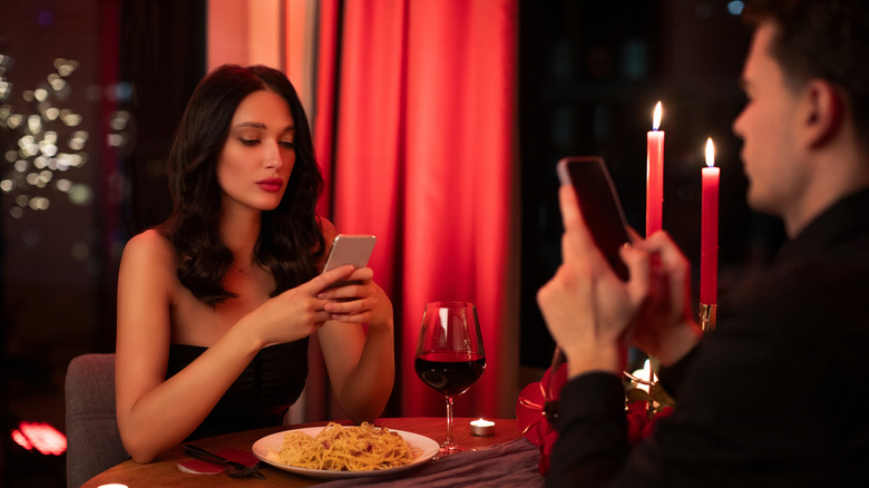 Man and woman are using their phones on a date