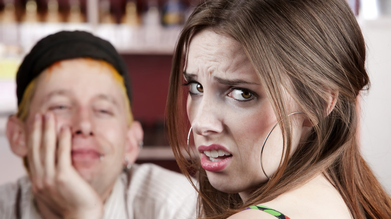 A woman looking at the camera while looking uncomfortable with her date