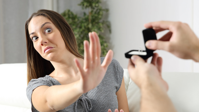 A woman is looking uncomfortable while rejecting an engagement ring