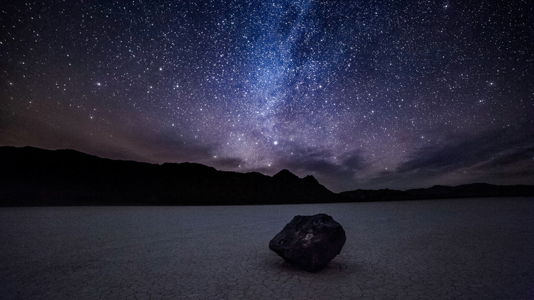 Night sky and the Milky Way over a moving rock at the Racetrack in Death Valley National Park in California