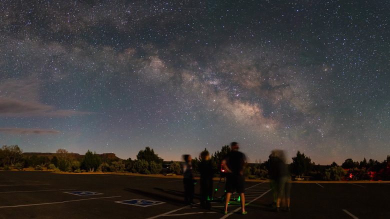 Night sky viewing in the visitor center parking lot of Natural Bridges National Monument. Panoramic view of the Milky Way Galaxy as the group gathers around a telescope to hear a Park Ranger talk.