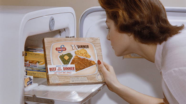 A woman taking a TV dinner out of the freezer