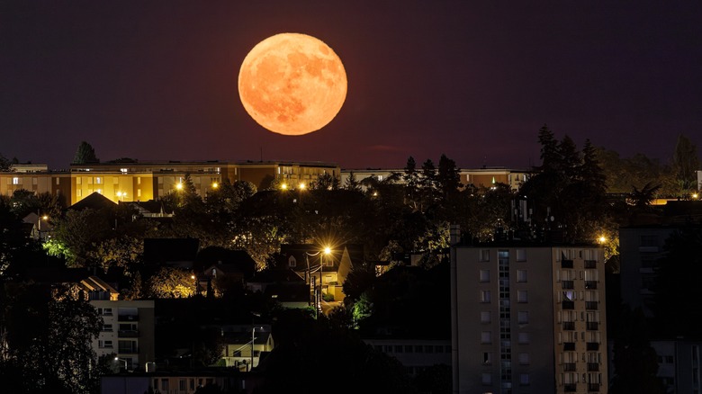 Orange full moon over a city