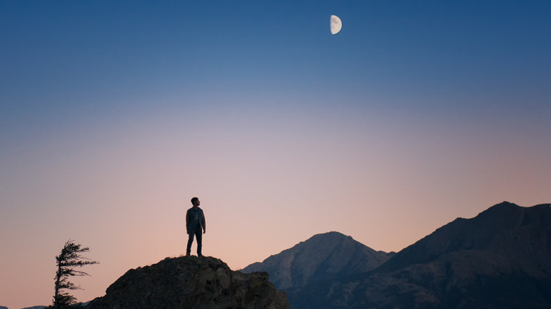 Man on mountain looking up at moon