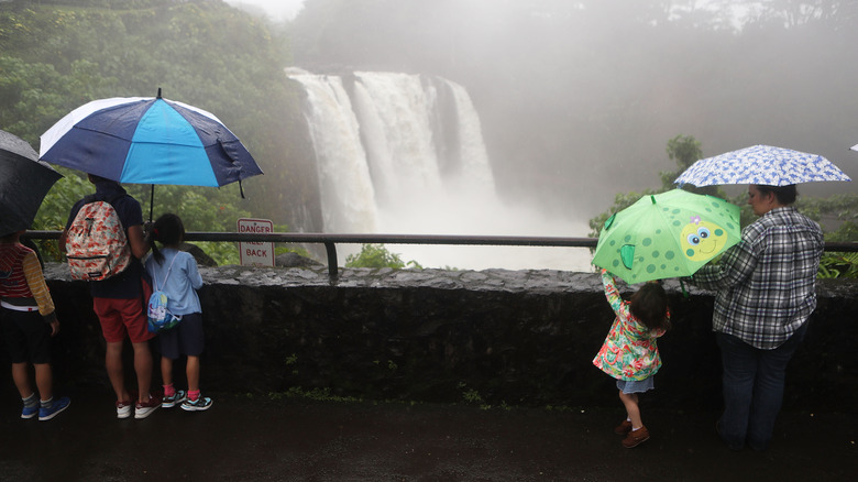People standing in rain looking at Rainbow Falls