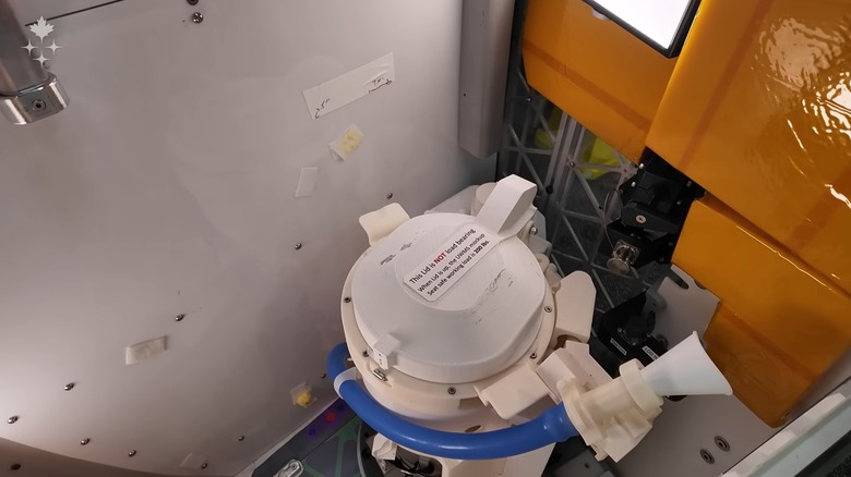 Artemis II mission specialist Jeremy Hansen from the Canadian Space Agency showing off a mock of the Orion's Universal Waste Management System