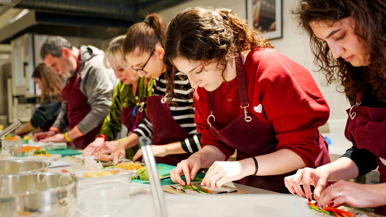 Group of people concentrating as they prepare sushi