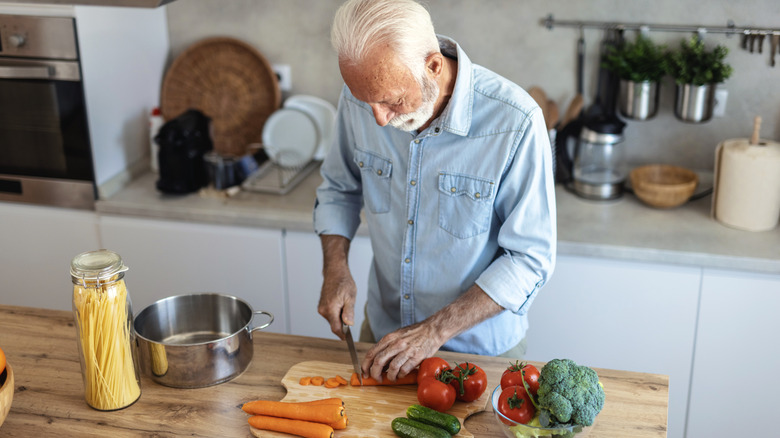 Older man chopping vegetables in the kitchen