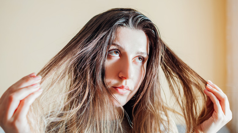 Woman looking annoyed about her hair being greasy and oily