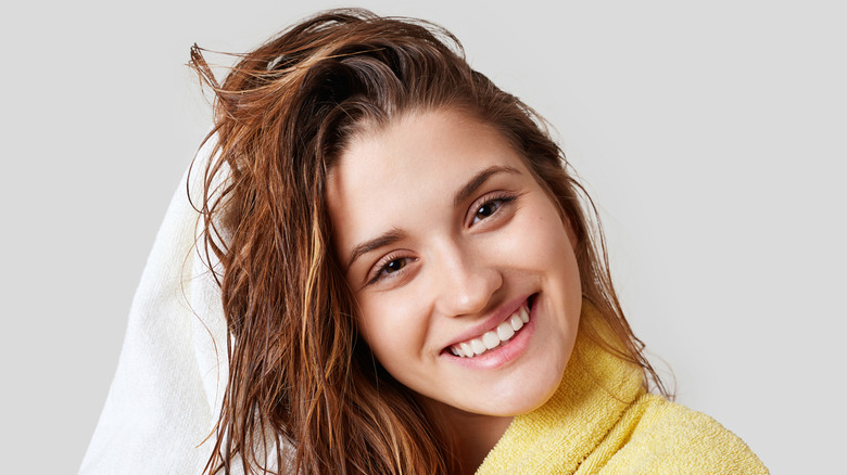 Woman happily towel-drying clean hair after showering