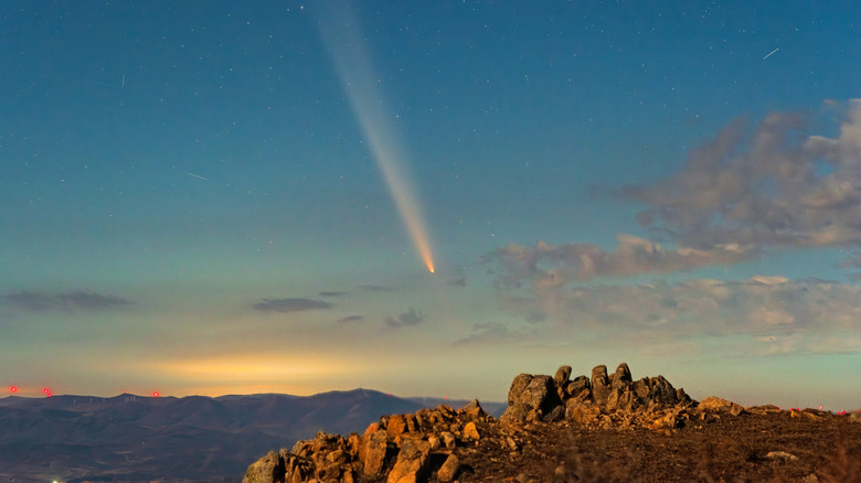 A comet is seen in the sky with a rocky landscape below