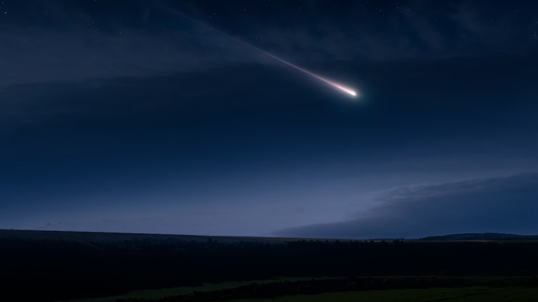 A meteor is seen in the night sky above some mountains