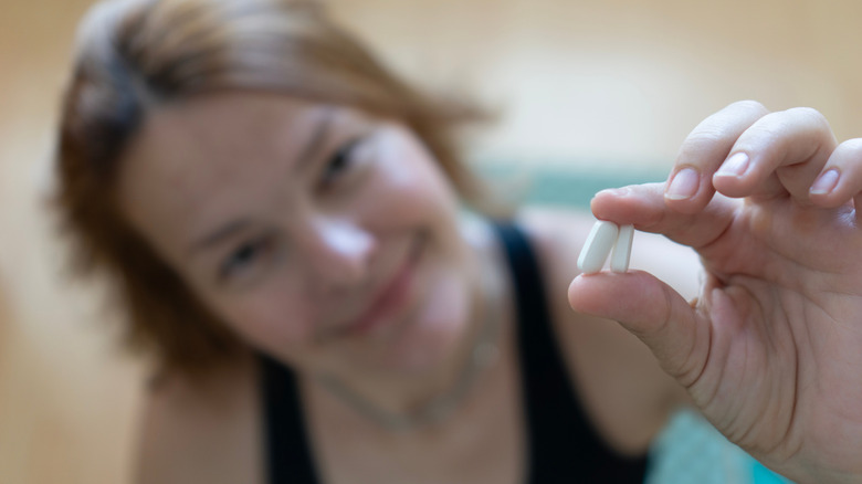 Woman holding two white GLP-1 tablets