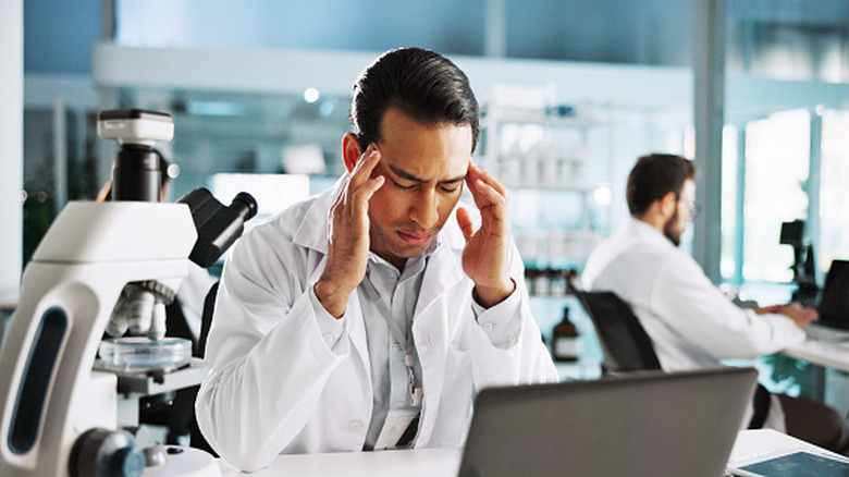 A frustrated scientist is holding his head
