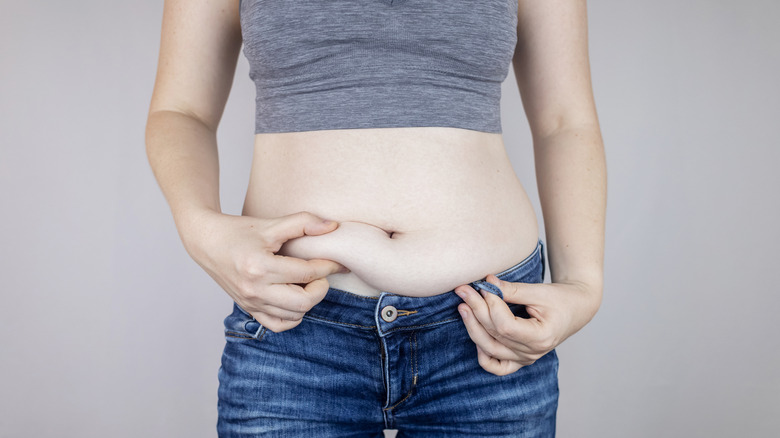Female in jeans pinching her belly fat