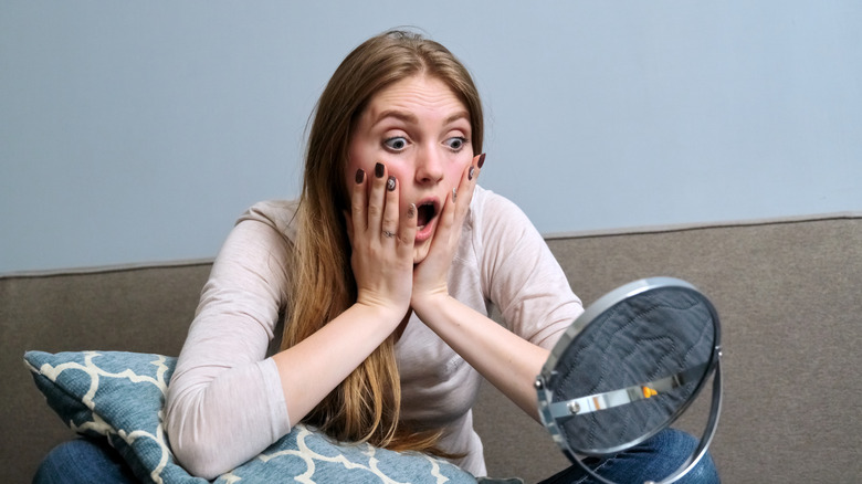 Woman looks frightened after looking in mirror