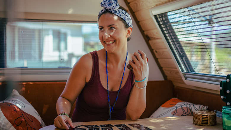 A woman smiling sitting in RV kitchen, laying out divination cards