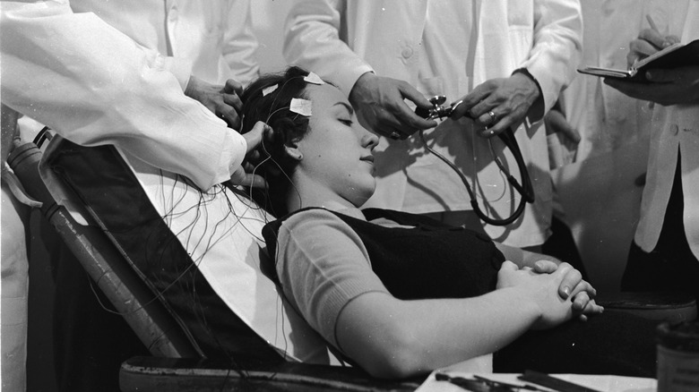 Scientists place electrodes on a woman's head.