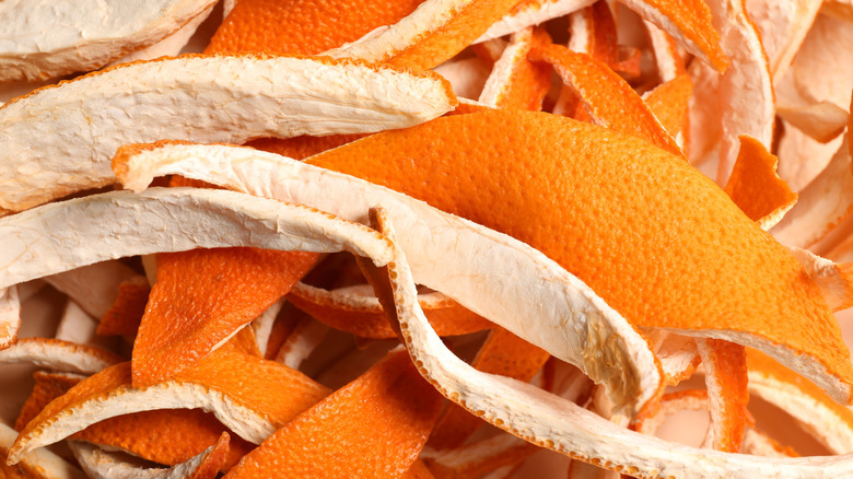 Orange peels are seen stacked on top of one another in a pile