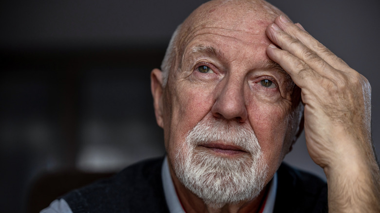Portrait of a senior man suffering holding his hand to his head