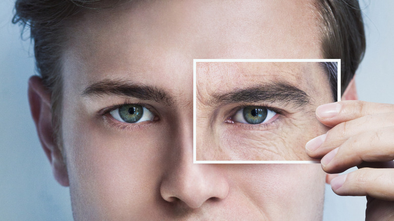 A young man holds up a picture an older version of his own eye