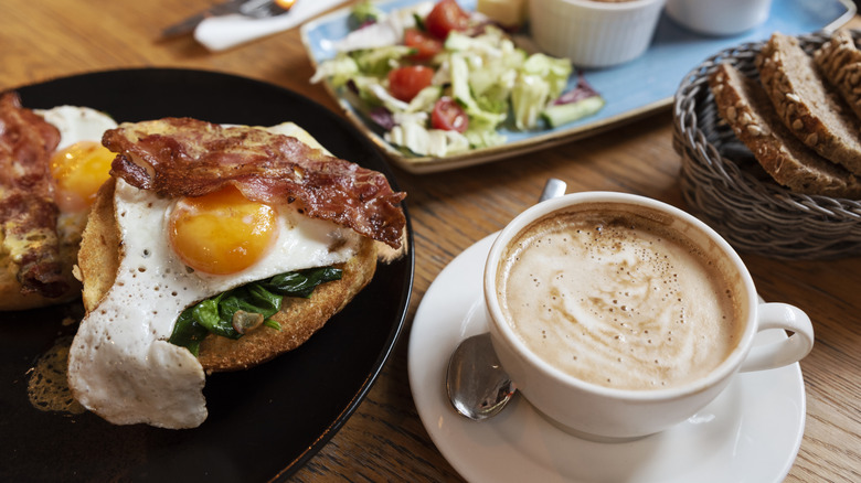 hearty breakfast of bacon and eggs on toast, coffee, bread, and a salad