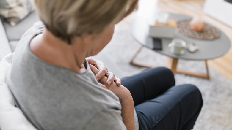 Woman sitting with hands over chest in pain