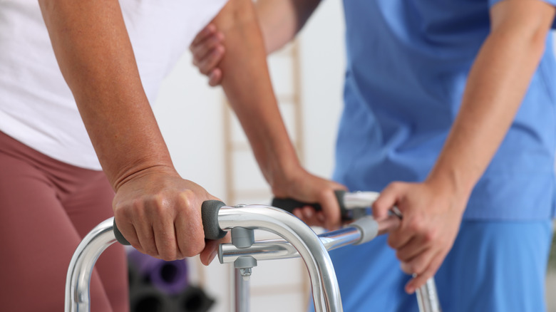 Physical therapist helping a person using a walker