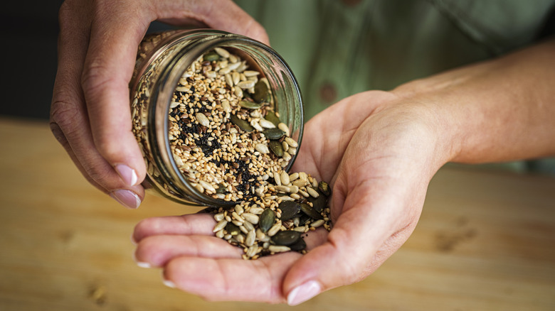Person pouring mixed seeds into hand